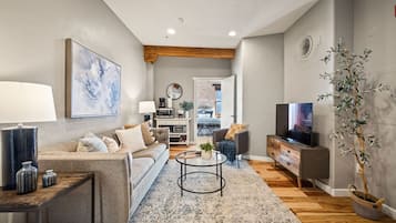 A modern living room with a sofa, coffee table, TV, and a plant.