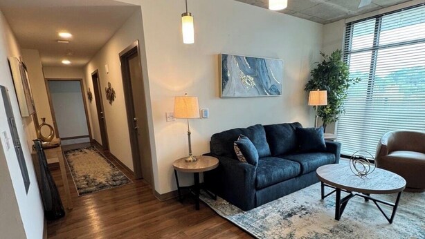 A modern living room with a dark sofa, round coffee table, and a large rug. There are pendant lights, a floor lamp, and a ceiling fan. - TopNotch 4-bedroom 4 bathroom (Birmingham)