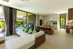 Ein modernes Wohnzimmer mit Sofa, Esstisch und Küchenbereich.