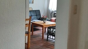 Ein Flur, der in einen Essbereich mit Tisch und Stühlen, einem kleinen Teppich und einer Tür mit Lichtschalter führt.