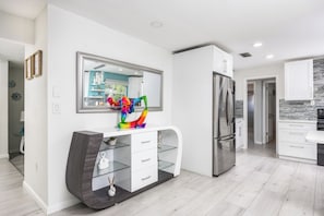 A modern kitchen with white cabinetry, a stainless steel refrigerator, and a colorful abstract sculpture on the countertop. - Sol Vacation:  Relaxing and Confort in one place (Largo)