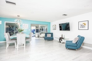A modern living room with a glass dining table, a blue sofa, and a white armchair. - Sol Vacation:  Relaxing and Confort in one place (Largo)