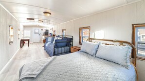 Een ruime, goed verlichte kamer met een groot bed, een tafeltje en een stoel.