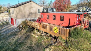 Een rode treinwagon met een houten platform en een geel bord met daarop 'Railroad Crossing'.
