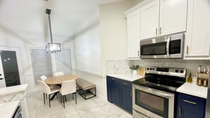 A compact kitchen with a dining area, featuring a microwave, stove, and cabinets. - Remote&Travel Workers Retreat: Beautiful Rockwall home near the Harbor (Rockwall)