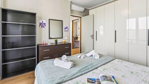 Ein Schlafzimmer mit Bett, Kleiderschrank, Kommode, Spiegel und Deckenleuchte.