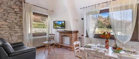 Una sala de estar amoblada con chimenea, televisor y comedor listo para una comida.