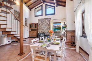 Une salle à manger spacieuse avec un plafond haut, un mur en pierre et une cheminée.