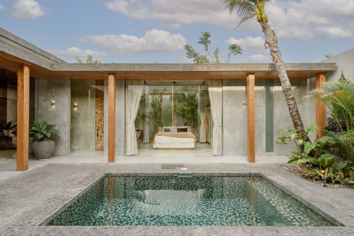 A modern bedroom with a large bed, a glass-enclosed bathroom, and a pool area.
