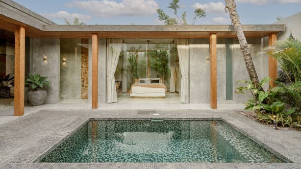 Un dormitorio moderno con una cama grande, un baño con paredes de cristal y una zona de piscina.