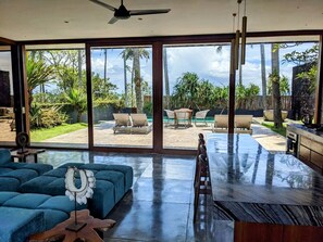 A spacious room with a large sliding glass door leading to an outdoor patio area. - Beachside Villa at Balian Surf Break (Selemadeg Barat)
