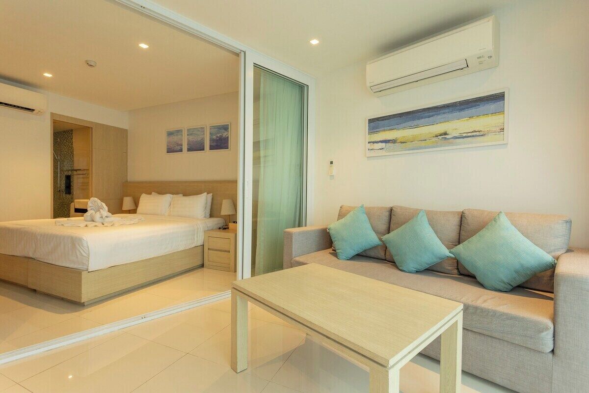A hotel room with a bed, a sofa, a table, and a painting on the wall.