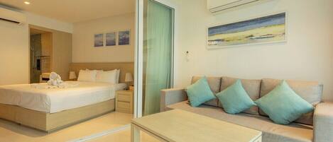 A hotel room with a bed, a sofa, a table, and a painting on the wall.