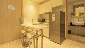 Una cocina compacta equipada con refrigerador, microondas y un pequeño comedor con taburetes.