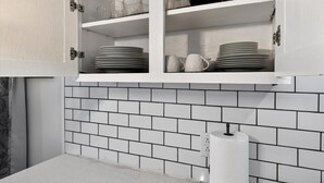 A kitchen with white cabinets, a tiled backsplash, and a roll of paper towels on the counter. - Premier Louisville home with exclusive home gym! (Louisville)