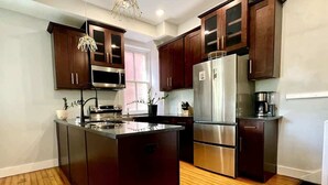A modern kitchen with dark wooden cabinets, stainless steel appliances, and a central island. - Exclusive 7BR Highlands home near KY Bourbon trail (Louisville)