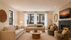 A living room with a sofa, armchairs, a coffee table, a fireplace, and a large window. - Iconic retreat w/ exclusive rooftop lounge & spa! (Nashville)