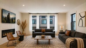 Ein Wohnzimmer mit Kamin, zwei Sofas, einem Couchtisch und einem großen Fenster mit Vorhängen.