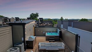 Eine Dachterrasse mit Whirlpool, Sitzgelegenheiten im Freien und Klimaanlagen.