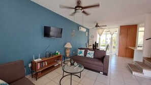 A living room with a sofa, a coffee table, a TV, and a bookshelf. - House in private condominium with pool just steps from the beach in Bucerias (Bucerías)