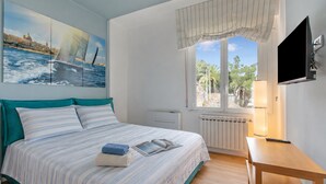 A bedroom with a bed, a window with a view, a TV, and a lamp. - Kenyon Charm - Total Sea View, Alassio, Italy (Alassio)