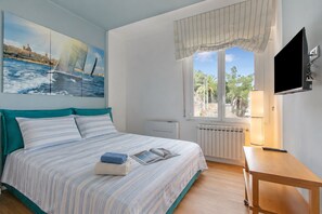 A bedroom with a bed, a window with a view, a TV, and a lamp. - Kenyon Charm - Total Sea View, Alassio, Italy (Alassio)