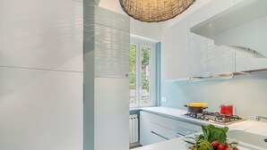 A modern kitchen with white cabinets, a gas stove, and a window overlooking greenery. - Kenyon Charm - Total Sea View, Alassio, Italy (Alassio)