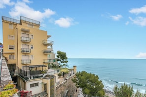 A multi-story building with balconies, a stone wall, and a view of the sea. - Kenyon Charm - Total Sea View, Alassio, Italy (Alassio)