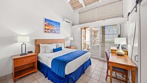 Una habitación de hotel con cama, mesitas de noche, escritorio y vistas al exterior.