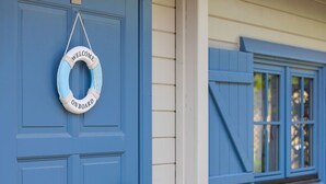 Una puerta azul con un flotador blanco y azul, un picaporte de metal y una ventana con contraventanas azules.