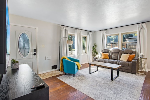 A modern living room with a sofa, a coffee table, and a TV stand. - Bright Beautiful 2BR Near Broadmoor with King Bed, Hot Tub, Deck & Putting Green (Colorado Springs)