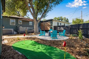 A backyard with a patio area, outdoor seating, and a small putting green. - Bright Beautiful 2BR Near Broadmoor with King Bed, Hot Tub, Deck & Putting Green (Colorado Springs)