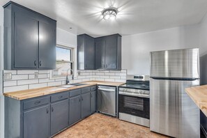 A modern kitchen with grey cabinets, a stainless steel refrigerator, and a dishwasher. - Bright Beautiful 2BR Near Broadmoor with King Bed, Jetted Tub, Yard & Deck (Colorado Springs)