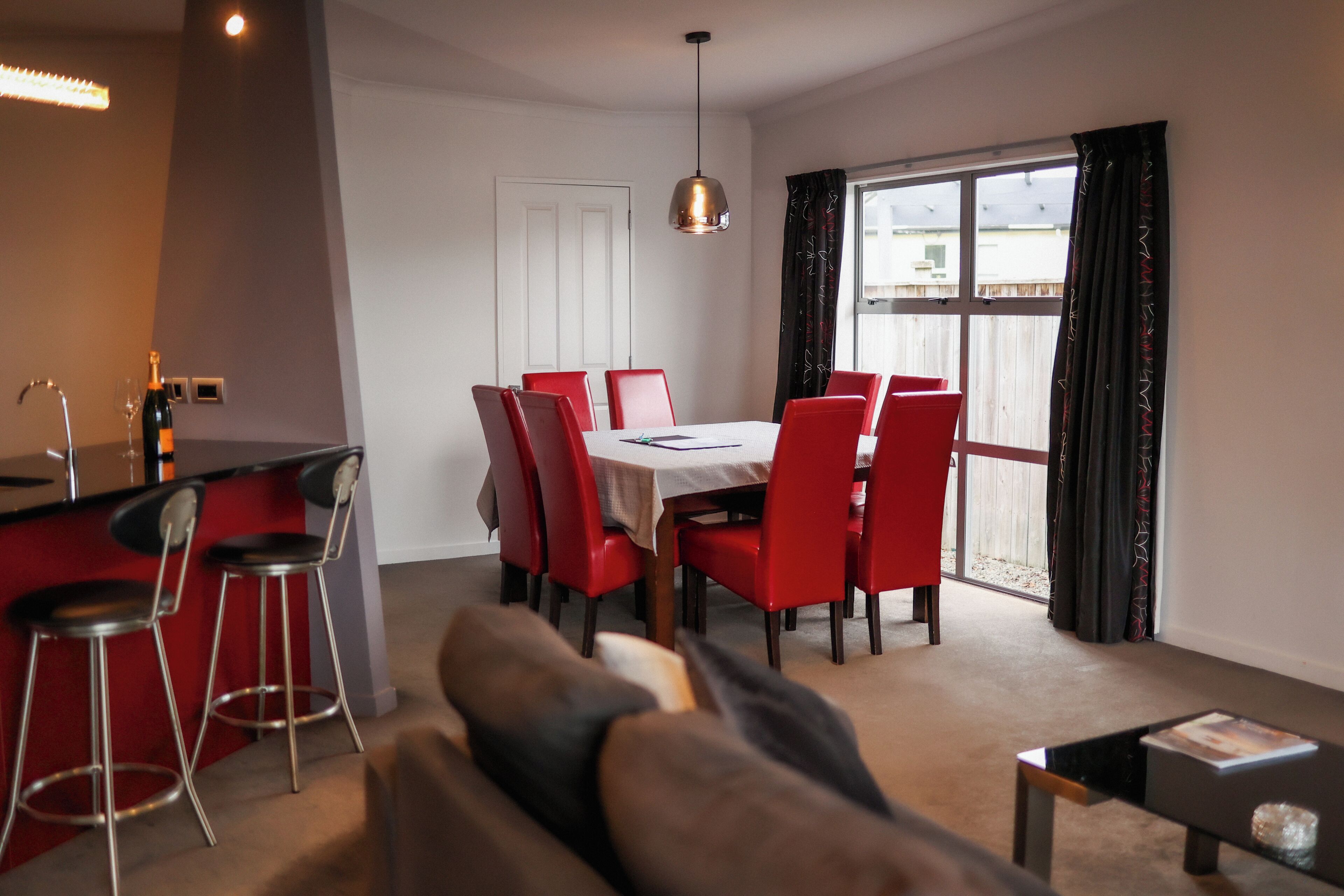 Une cuisine moderne avec un coin repas, des chaises rouges et une grande fenêtre.