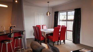 A modern kitchen with a dining area, red chairs, and a large window. - Martinborough Retreat with Hot Tub (Martinborough)