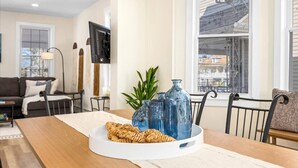 Een eethoek met een houten tafel, een witte placemat en blauwe glazen vazen.