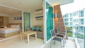 Een moderne hotelkamer met een bed, een bank en een balkon met een glazen hekwerk.