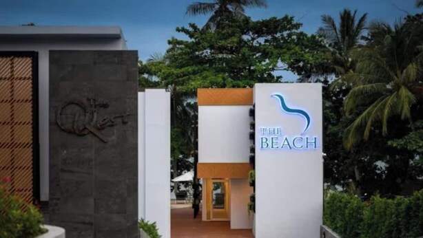 Een moderne entree van een gebouw met een bord waarop 'The Beach' staat.
