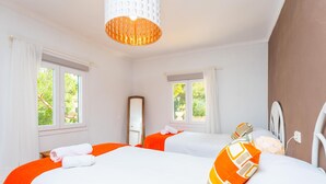 Ein Hotelzimmer mit zwei Betten, großen Fenstern, einem Spiegel und einer Pendelleuchte.