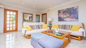 Ein geräumiges Wohnzimmer mit zwei Sofas, einem Couchtisch und einem großen Gemälde an der Wand.