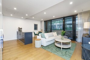 Una sala de estar moderna con un sofá, una mesita de centro y una cocina con mostrador y armarios.