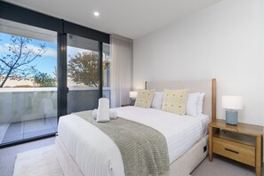 A modern hotel room with a large bed, two bedside tables, and a view through a sliding glass door. - Scandi Apartment Above Kingston Dining + Balconies (Kingston)