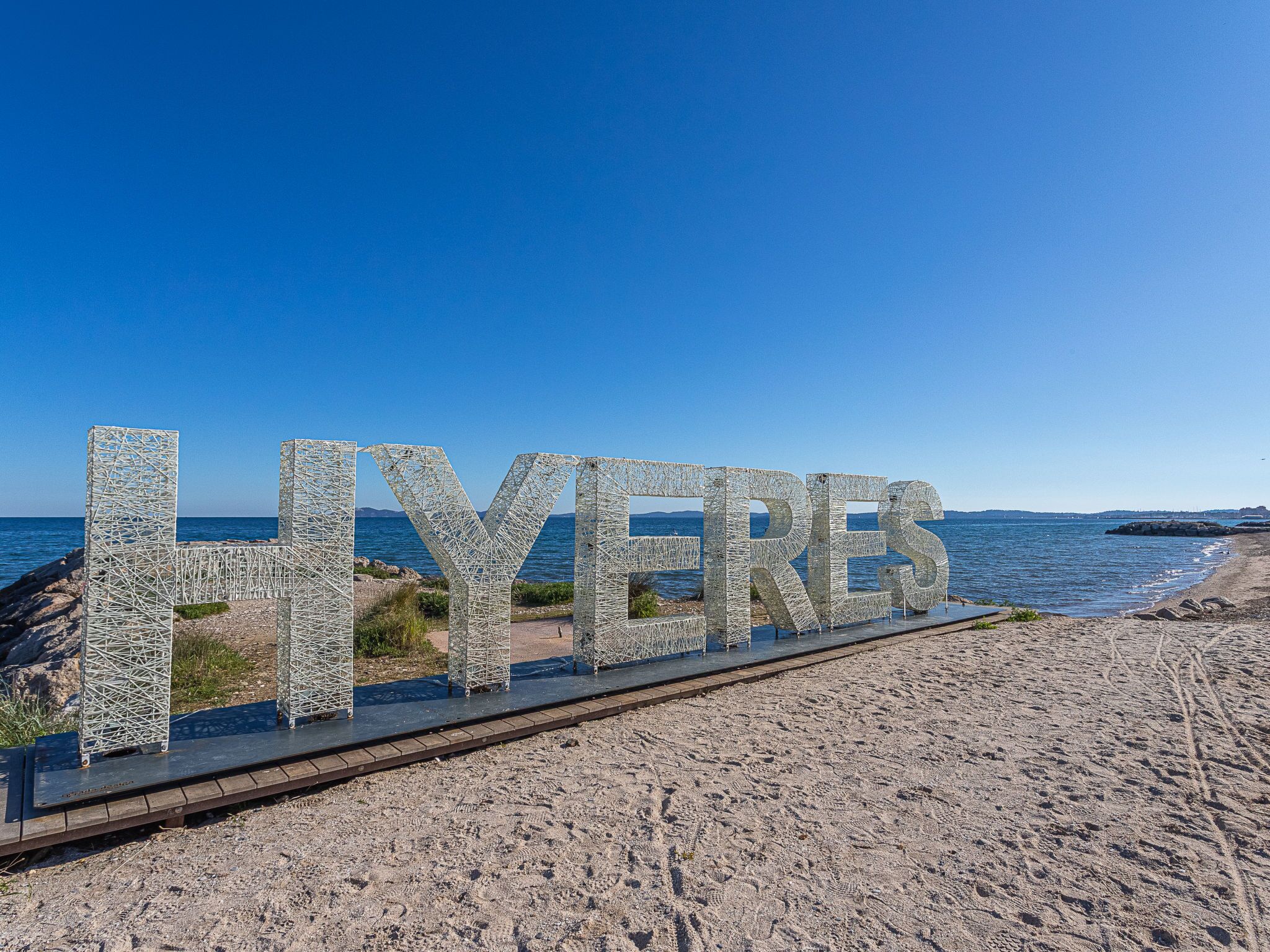 A beach with the word "LYERES" spelled out in large letters on a boardwalk.