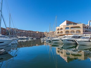 A marina with multiple boats docked, a large building with balconies, and a clear blue sky. - Port de la Gavine I by Interhome (Hyères)