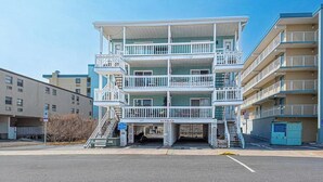 A multi-story hotel with balconies, a central staircase, and a parking area. - Sinbad – Newly Renovated • Steps to the Beach • Midtown OC 2BR 1.5 BA (Ocean City)