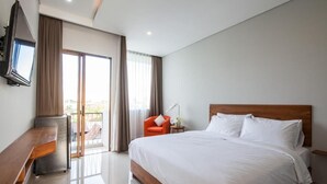 A hotel room with a large bed, a desk, a chair, a TV, and a balcony. - Eclipse Kerobokan (Seminyak)