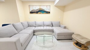 A modern living room with a sectional sofa, a glass coffee table, and a wooden chair.