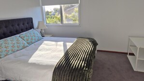 Une chambre à coucher avec un lit, une fenêtre, une table de chevet et une chaise.