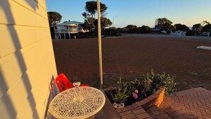 Un espace extérieur aménagé avec une table et des chaises, un chemin en briques et une vue sur un terrain de sport.