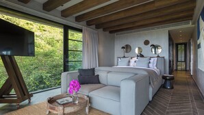 Une chambre moderne avec un canapé, un téléviseur et une vue sur la verdure.